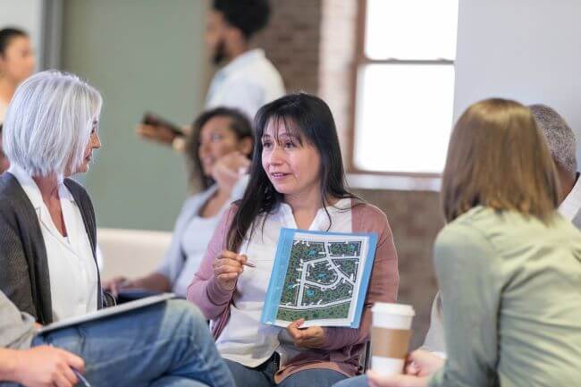 An HOA representative is sitting in a circle talking to other people about neighborhood plans.