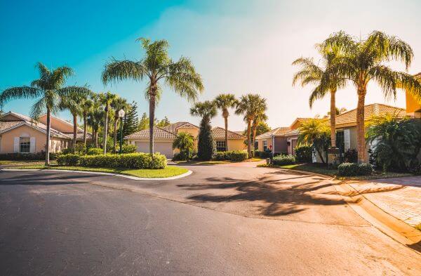 A residential neighborhood with palm trees and houses on a sunny day.